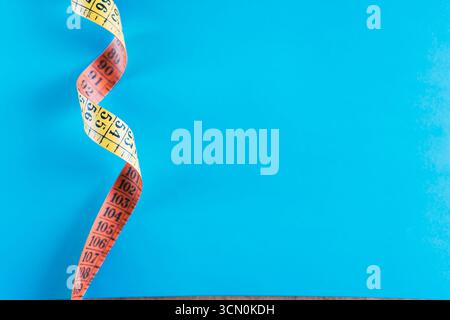 Ein gelbes Maßband auf blauem Hintergrund. Stockfoto