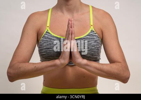 Frau im Sport-BH mit Händen in Gebetsposition für Yoga Stockfoto