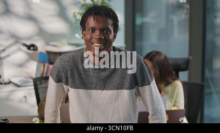 Porträt im Büro glücklicher lächelnder afroamerikanischer informeller Geschäftsmann sorgloser Geschäftsmann männlicher Mann Arbeiter Startup-Besitzer, der auf die Kamera blickt Stockfoto