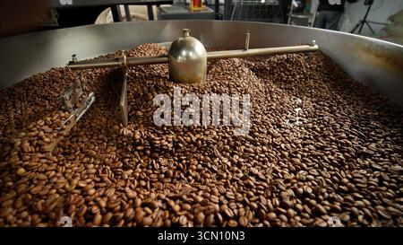 Frisch geröstete Kaffeebohnen Kühlung in großer industrieller Mischmaschine Röstermischung in moderner Fabrik aromatische braune Körner mischen Kakao Stockfoto