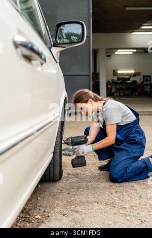 Weibliche Reifenarbeiterin wechselt das Autorad in der Garage Stockfoto