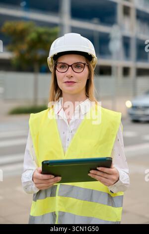 Eine Ingenieurin trägt einen Schutzhelm, der ein Tablet hält Stockfoto