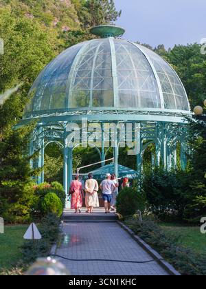 Glas- und Metallpavillon im Garten mit Besuchern Stockfoto
