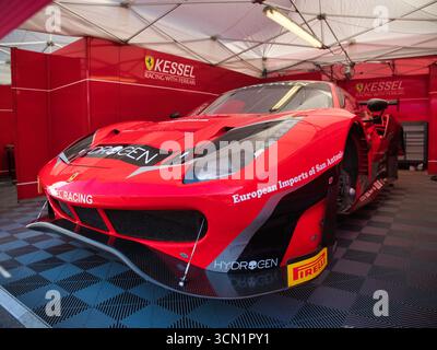 Hochleistungs-Ferrari-Rennwagen in der Boxengarage – Eine detaillierte Aufnahme eines roten Ferrari-Rennwagens, der in einer professionellen Boxengarage geparkt ist und dessen ag präsentiert Stockfoto