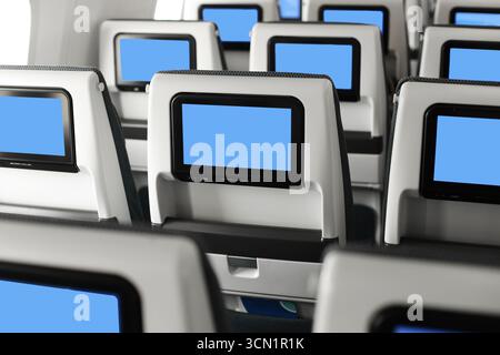 Kabinensitze im Flugzeug mit persönlichen Bildschirmen. Nahaufnahme der Innenreihen des Flugzeugs. Moderner Hintergrund für den Reiseverkehr. Komfort-Technologie für den Beifahrer Stockfoto