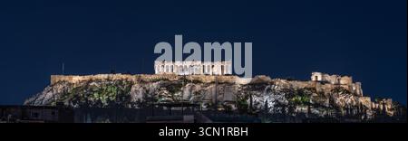 Panoramablick auf den beleuchteten Akropolis-Hügel mit Parthenon- und Propyläentempeln bei Nacht in Athen, Griechenland. Mai 2025. Stockfoto