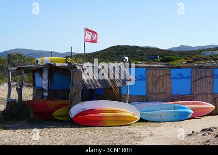 Farbenfrohe Strandhütte Mit Surfbrettern Auf Sand Unter Blauem Himmel, Küstenferienszene. Plage de la Tonnara, Korsika, Frankreich Stockfoto