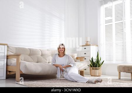 Frau mit Fernbedienung der Klimaanlage zu Hause Stockfoto