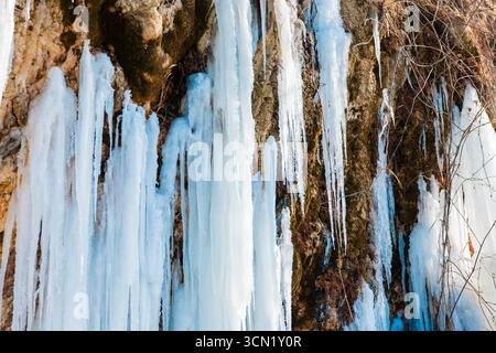 Majestätischer gefrorener Wasserfall mit langen Eiszapfen auf Felsen im Winter. Stockfoto