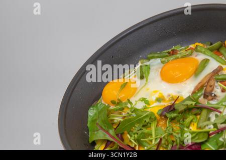 Zwei Spiegeleier mit frischem Gemüse, Bohnen, Mais und Gemüse in einer Pfanne gekocht, Konzept des gesunden hausgemachten Frühstücks. Stockfoto