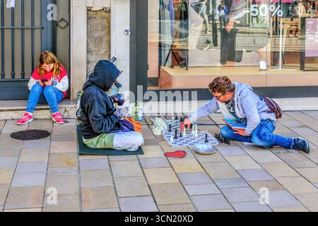 Zwei Männer, einer mit einer kleinen Tochter, der andere Obdachlose, spielen Schach auf dem Gehsteig der Rue nationale, Tours, Indre-et-Loire (37), Frankreich. Stockfoto