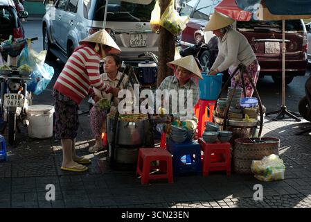 Ho-Chi-Minh-Stadt, Vietnam - 4. Juni 2015: Typischer Straßenstand mit Pho-Nudelsuppe, vier vietnamesische Frauen mit konischen Hüten, die traditionelle Suppe in Schüsseln gießen und Kunden servieren Stockfoto
