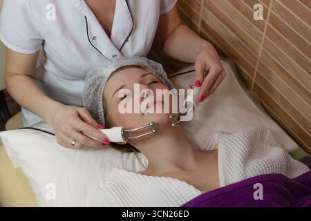 Beauty-Therapie: Frau mit Mikrostrom im Gesicht für Lifting und Lymphdrainage. Stockfoto