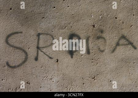 Graffiti auf verwitterter Wand gibt SRBNA mit Bold Black Sprühfarbe, Urban Texture, Beton wieder. Bonifacio, Korsika, Frankreich Stockfoto