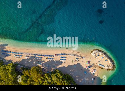 Blick auf den Strand Makarska Riviera in Podgora gepflegte Sonnenliege Linien ruhiges Morgenmeer und schützender Felssteg Stockfoto