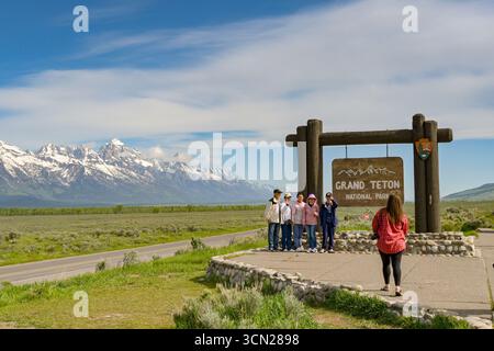 Jackson, Wyoming, USA - 28. Mai 2025: Gruppe von Touristen posiert vor einem Schild am Eingang zum Grand Teton National Park Stockfoto