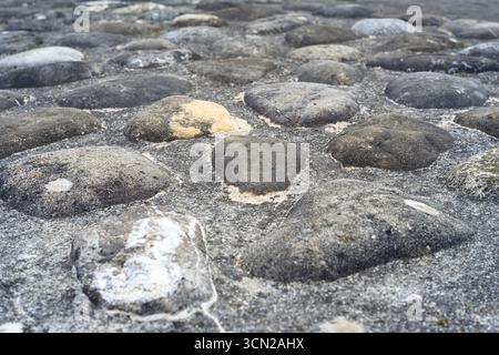 Nahaufnahme eines Pflasterpflasters mit unebenen Steinen. Stockfoto