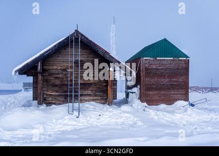 Holzhütte im Schnee der Berge. Kleine Holzhütten im Schnee an den Hängen eines Berges Stockfoto