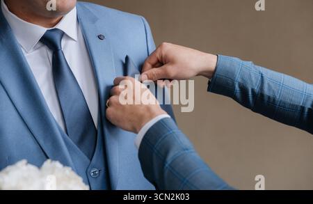 Nahaufnahme des Bräutigams, der vor der Hochzeit das Taschenfeld in blauem Anzug verstellt Stockfoto