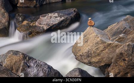 Zwei Kieselsteine, die auf Felsen im Wasserfall ausbalanciert sind, veranschaulichen Widerstandskraft, Stärke, Gleichgewicht, Ruhe und Ruhe. Icicle Creek WA Stockfoto