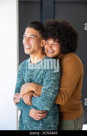 Zwei Männer stehen im Eingangsbereich und umarmen sich, tragen Strickpullover und lächeln Stockfoto