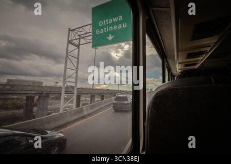 Straßenbild von einem Busfenster auf einer Quebec-Straße aus mit einem grünen Schild in Richtung Ottawa und Gatineau, Verkehrsstraßen, Überführungen und einem Clou Stockfoto