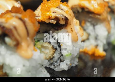 Sushi-Brötchen mit bunten Belägen auf einer Platte Stockfoto
