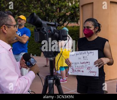 Burbank, Usa. September 2025. Ein Demonstrant mit einem Plakat wird vor den Walt Disney Studios während einer Demonstration über die Aussetzung von Jimmy Kimmels Late-Night-Show interviewt. (Foto: Lela Edgar/SOPA Images/SIPA USA) Credit: SIPA USA/Alamy Live News Stockfoto