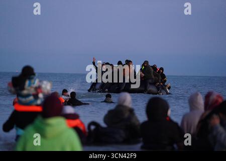 Eine Gruppe von Menschen, die als Migranten gelten, waten in der Nähe von Gravelines in Frankreich ins Meer, um sich einem Boot anzuschließen. Bilddatum: Freitag, 19. September 2025. Stockfoto