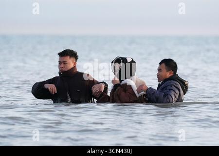 Eine Gruppe von Menschen, die als Migranten gelten, waten in der Nähe von Gravelines in Frankreich ins Meer. Bilddatum: Freitag, 19. September 2025. Stockfoto