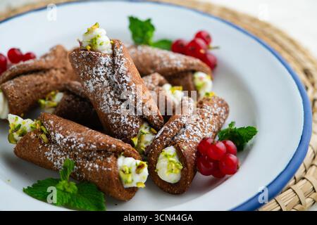 Sizilianische Cannoli gefüllt mit Ricotta-Käse-Sahne und garniert mit gehackten Pistazien. Stockfoto