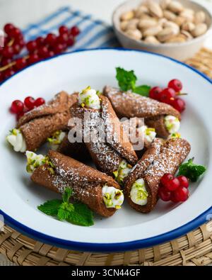 Sizilianische Cannoli gefüllt mit Ricotta-Käse-Sahne und garniert mit gehackten Pistazien. Stockfoto