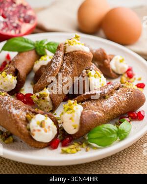 Sizilianische Cannoli gefüllt mit Ricotta-Käse-Sahne und garniert mit gehackten Pistazien. Stockfoto