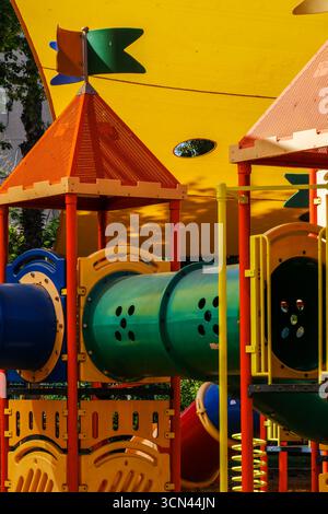 Farbenfroher Spielplatz-Tunnel und Kletterstruktur mit schattigem Baldachin. Stockfoto