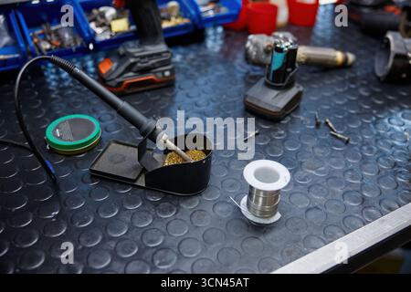 Ein Lötkolben liegt auf einem Arbeitstisch mit Lötkolben und Lötkolben auf Stockfoto