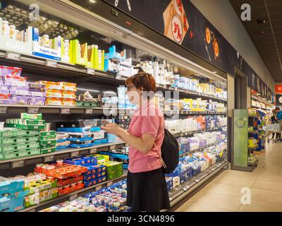 Cremona, Italien 17. September 2025 Frau, die ein Produktetikett in der Milchabteilung eines preisgünstigen Lebensmittelgeschäfts sorgfältig untersucht und eine Auswahl trifft Stockfoto