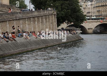 Paris, Frankreich - 9. Juni 2023: Menschen bleiben am Ufer der seine und unterhalten sich, trinken und Spaß haben. Stockfoto