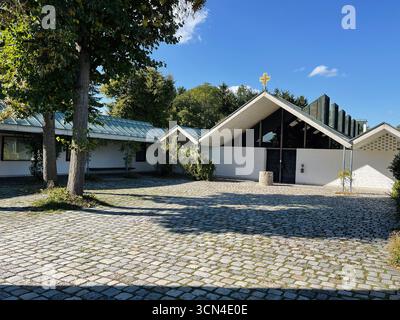 Dachau, Deutschland - 29. September 2022: Außenfassade der modernen Kapelle im Konzentrationslager Dachau mit umliegenden Bäumen Stockfoto