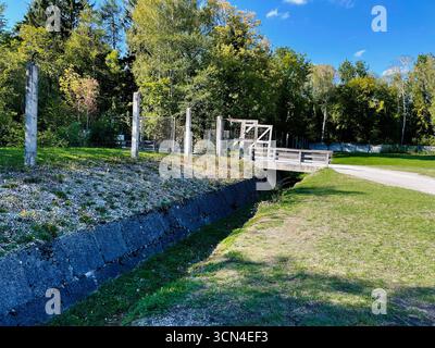Dachau, Deutschland - 29. September 2022: Zäune und Weg im Konzentrationslager Dachau, Deutschland, umgeben von ruhigem, sonnigem Grün. Stockfoto