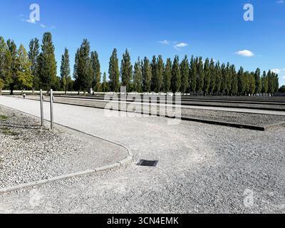 Dachau, Deutschland - 29. September 2022: Wege im Konzentrationslager Dachau, umgeben von Bäumen an einem sonnigen Tag Stockfoto