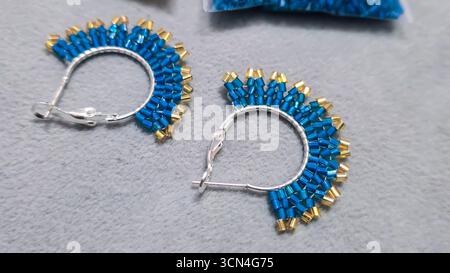 Handgefertigte Ohrringe mit Perlen und Glasperlen auf hellem Hintergrund. Produktvorführung. Modetrends. Kopierbereich Stockfoto
