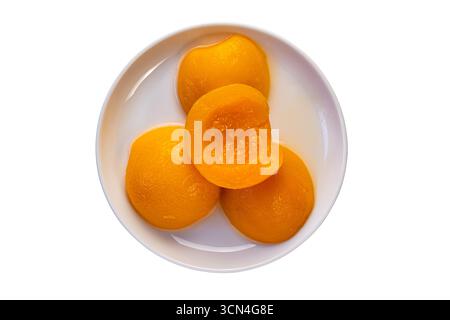 Draufsicht von konservierten Pfirsichhälften in Sirup in weißer Keramikplatte isoliert auf weißem Hintergrund mit Schnittpfad. Stockfoto