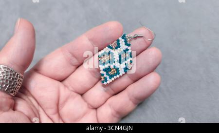 Handgefertigte Ohrringe mit Perlen und Glasperlen auf hellem Hintergrund. Produktvorführung. Modetrends. Kopierbereich Stockfoto