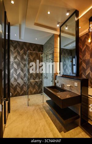 Ein modernes Bad mit dunklen Holzakzenten, einer Glasdusche und eleganten Armaturen. Das Design schafft einen luxuriösen und sauberen Raum für Entspannung und p Stockfoto