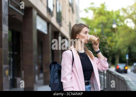 Frau genießt Kaffee im Freien, gekleidet in stilvollem rosa Blazer Stockfoto