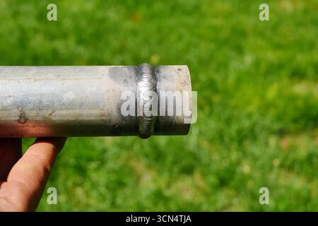 Metallrohr mit einer Schweißnaht in der Hand des Menschen des Schweißers Stockfoto