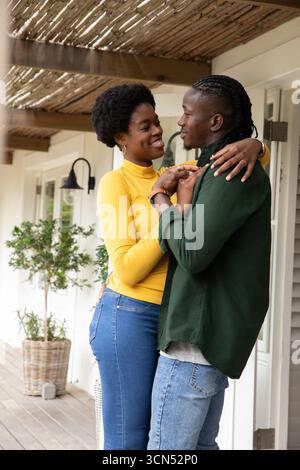 afroamerikanisches Paar umarmt, lächelt auf der Veranda unter Pergola mit Laterne, Kopierraum Stockfoto