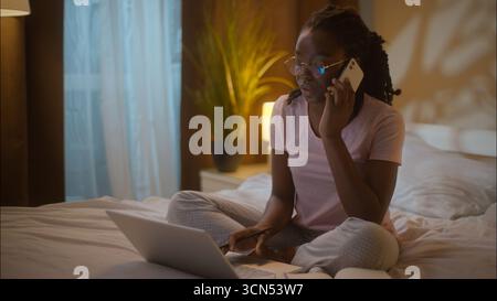 Multitasking afroamerikanische Geschäftsfrau Studentin weibliches Mädchen Geschäftsfrau in Brille sprechen Handy anrufen Arbeit Laptop freiberuflich schreiben Stockfoto