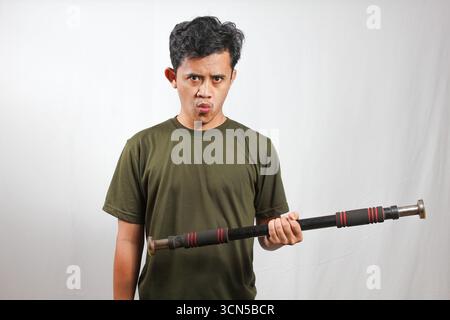 Asiatischer Mann mit grünem T-Shirt, der Krafttraining mit leichten Kurzhanteln macht Stockfoto