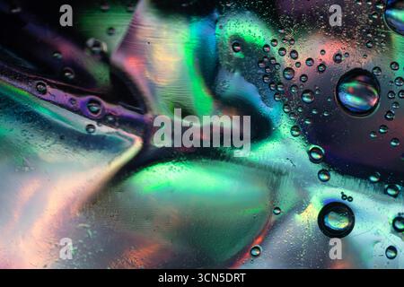 Abstraktes Makrofoto von flüssigen Luftblasen auf einer glatten Oberfläche mit lebhaften Farben von Grün, Blau, Violett und Rosa, die sich verschmelzen, um ein schimmerndes r Stockfoto